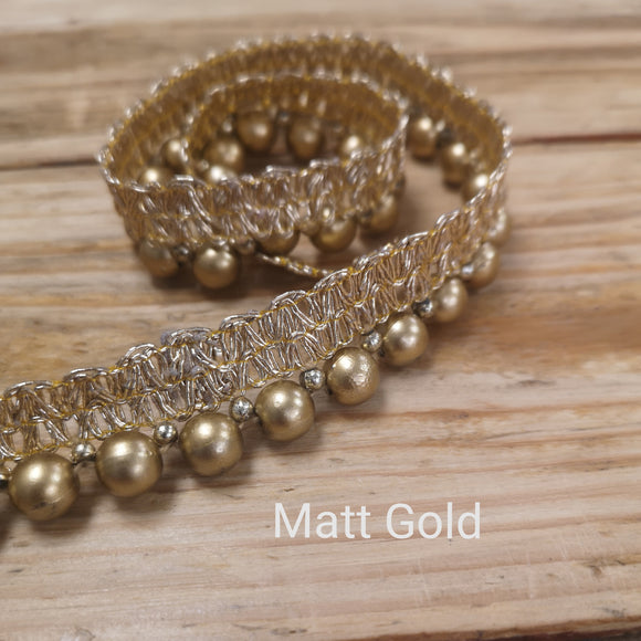 Matt gold bead trim on metallic gold gimp braid.