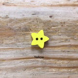 small wooden star button painted yellow on wooden surface.