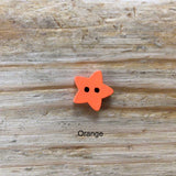 small wooden star button painted orange on wooden surface